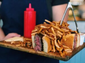 A perfectly cooked burger piled high with french fries at Good Luck restaurant in Rochester NY