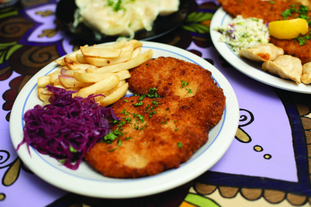 A plate of schabowy breaded pork cutlet with fries and pickle salad at Polska Chata restaurant in Rochester NY