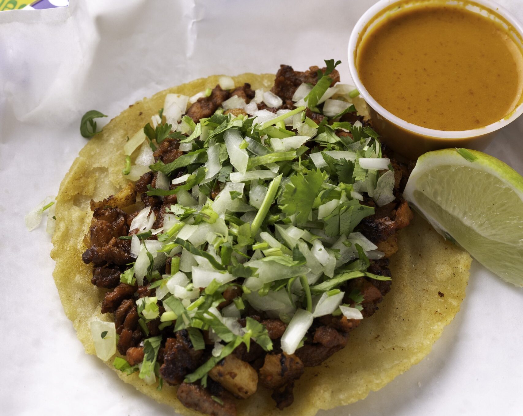 An al pastor taco with dipping sauce at Peach Blossom Mexican restaurant in Rochester NY