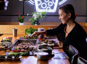 A diner cooks meat at the table grill at Taichi Iron BBQ Grill & Bar Korean barbecue restaurant at the Mall at Greece Ridge in Rochester NY