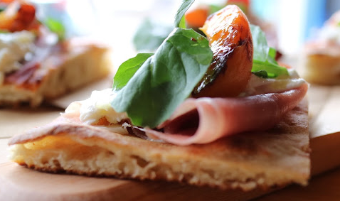 A piece of flatbread topped with prosciutto, tomato and basil at Fiorella restaurant in Rochester NY