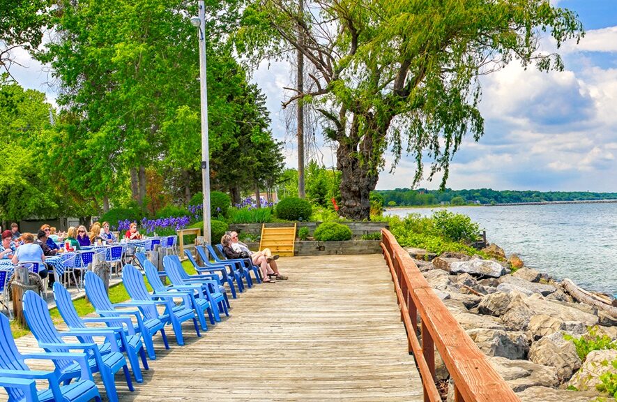 A row of bright blue beach chairs on the wooden deck overlooking Lake Ontario at Castaways on the Lake in Rochester NY