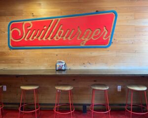 Bar seating with sign inside The Playhouse Swillburger bar and restaurant in Rochester NY