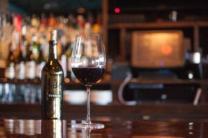 A bottle and glass of red wine on the bar counter at Avvino restaurant in Rochester NY