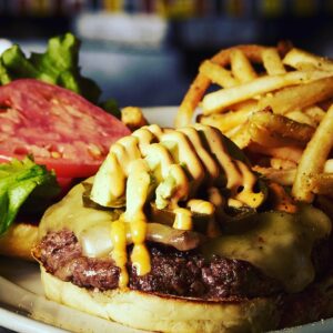 An open face cheeseburger with tomato, lettuce and fries on the side at The Gate House restaurant in Village Gate Rochester NY