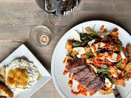 A table set with a flat iron steak salad and glass of red wine at Jojo Bistro and Wine Bar in Pittsford NY