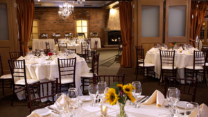 The elegant dining room with white tablecloths, crystal chandeliers, and exposed brick walls at Pane Vino on the Avenue restaurant in Pittsford NY