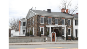 The 200 year old Farmers Creekside Tavern and Inn with stone facade and white trim in Le Roy NY