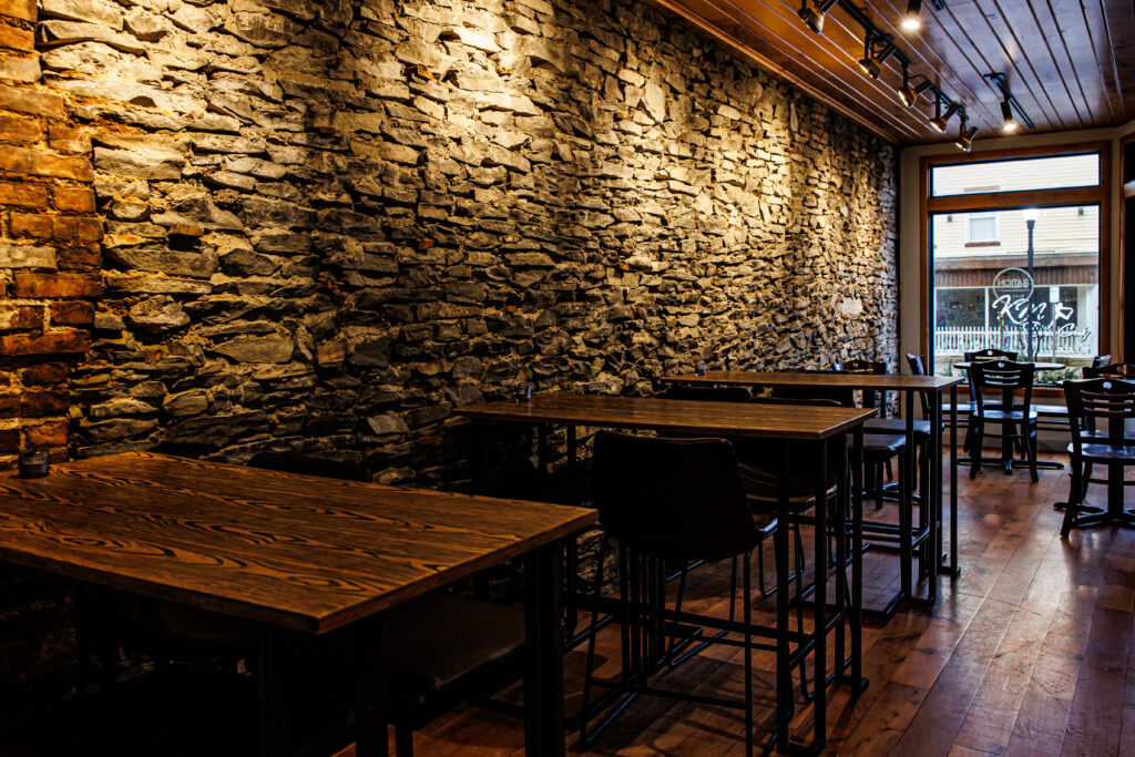 The dining room with exposed stone walls and wooden bar tables Ration Wine Bar in Perry, NY