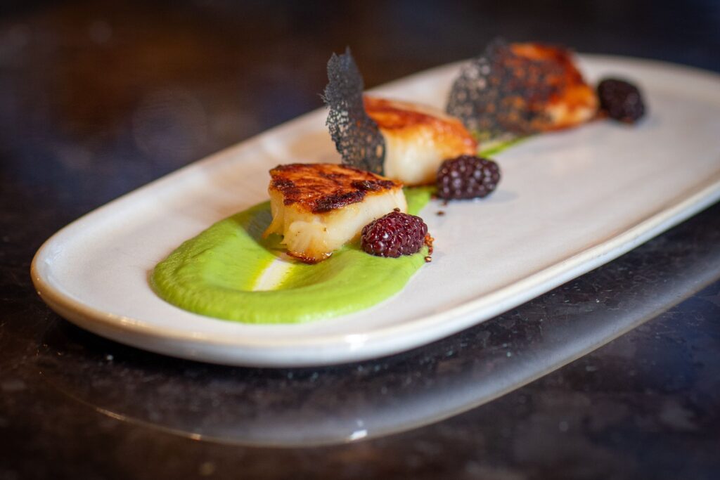 A dish with scallops made by Ashley Perez for Horizons Modern Kitchen and Bar at Woodcliff Hotel and Spa in Rochester NY