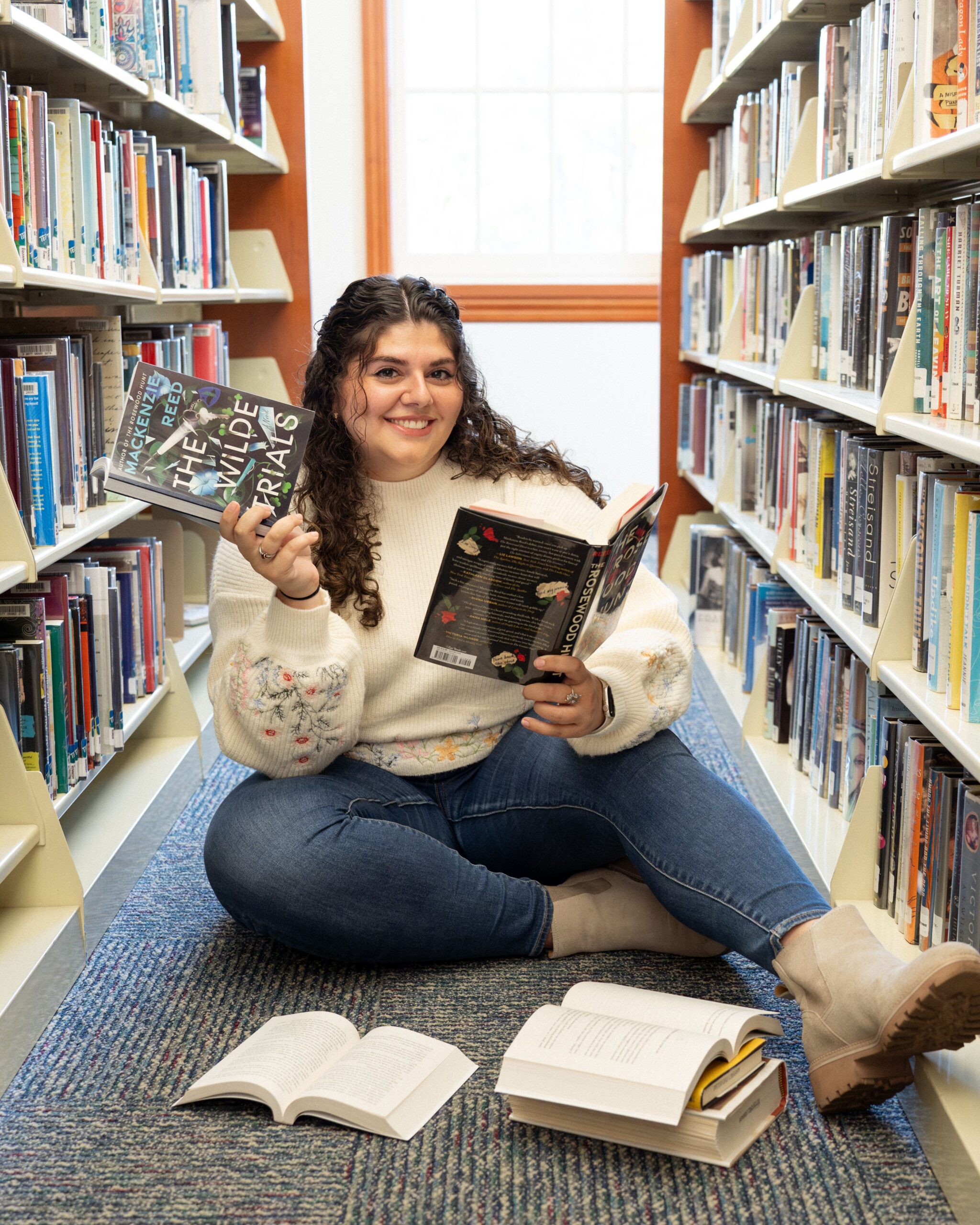 Mackenzie Reed, author of The Rosewood Hunt and The Wilde Trials, poses at the library in her hometown of Rochester NY