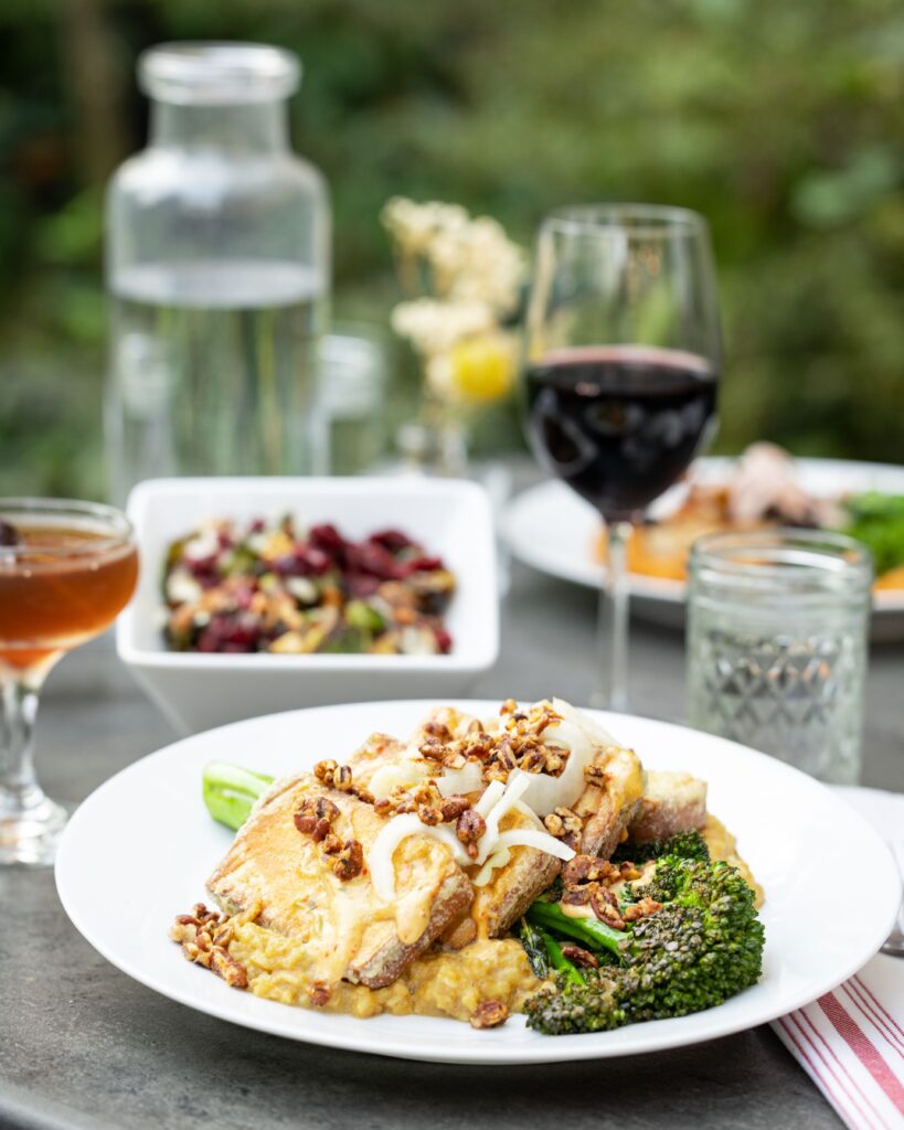 A plate of crispy tofu, pumpkin risotto, grilled broccolini, tarragon harissa aioli, pickled fennel, and candied pecans at The Owl House vegan restaurant in Rochester NY