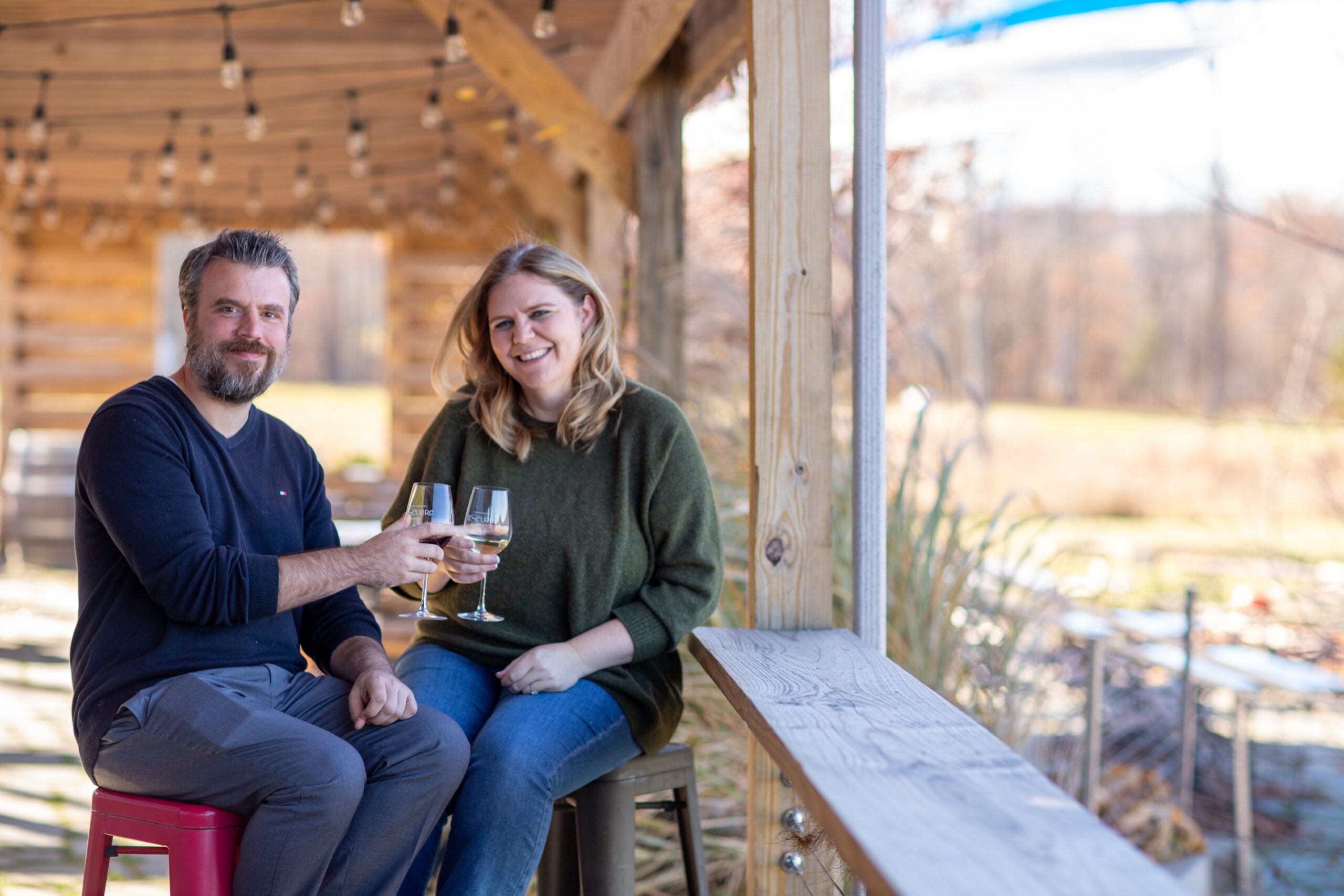 Christopher and Sarah Mead raise a glass while sitting at an outdoor terrace on the Keuka Wine Trail in the Finger Lakes region of NY