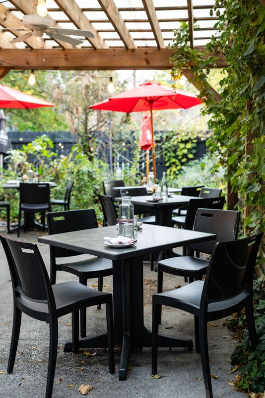 Outdoor tables under a pergola at The Owl House vegan restaurant in Rochester NY