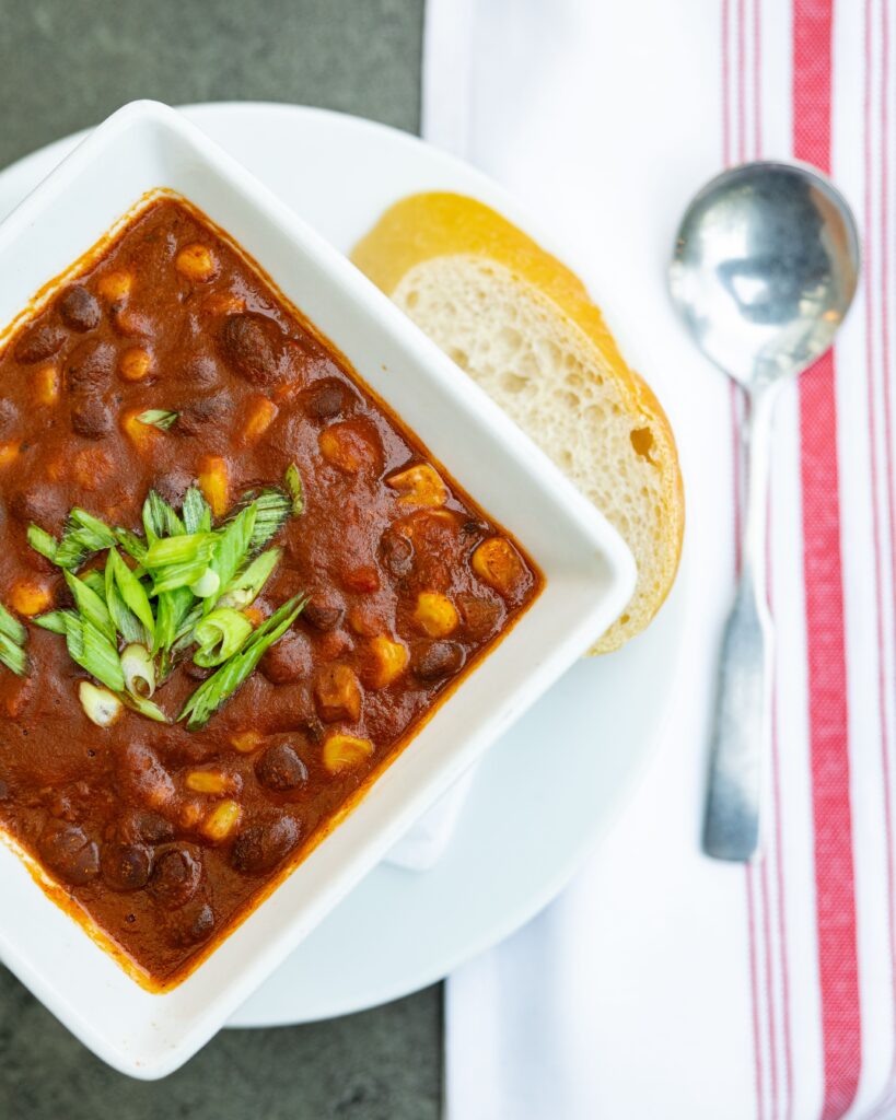 A bowl of black bean and corn chili garnished with green onions at The Owl House vegan restaurant in Rochester NY