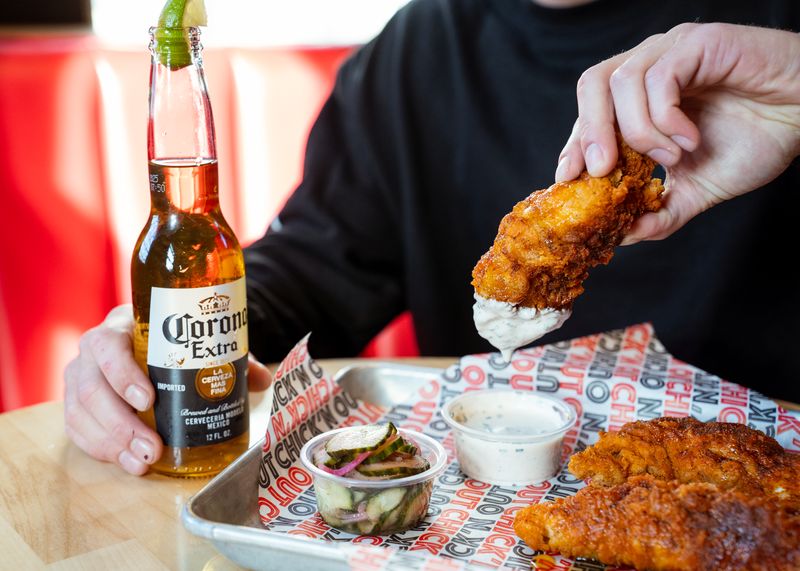 A diner enjoys a Corona beer with Hot and Stung: hot chicken tenders with honey, dipping sauce, and pickles at Chick'n Out restaurant in Rochester NY