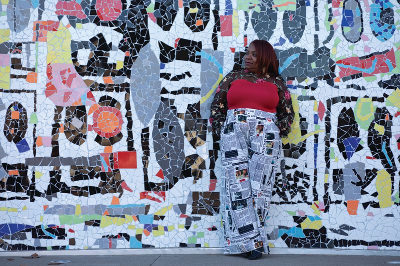 Clianda Florence poses in front of mosiac mural wall outside in Rochester, N.Y.