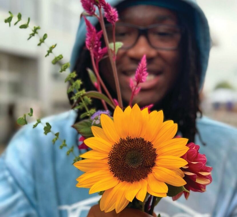 Young man holding bright sunflower in Rochester, NY.