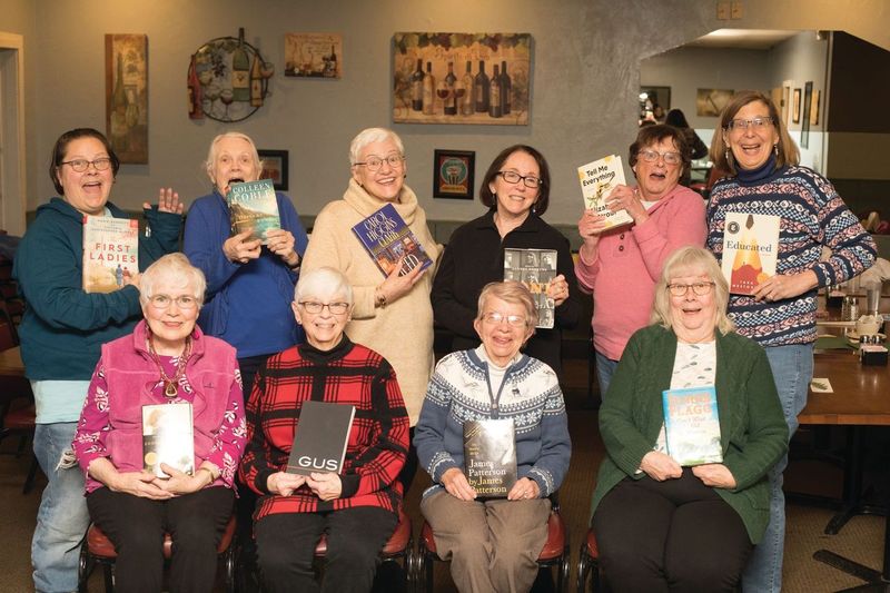 Ten ladies posing with books in their hands as part of the Hilton book guild in Rochester, N.Y.