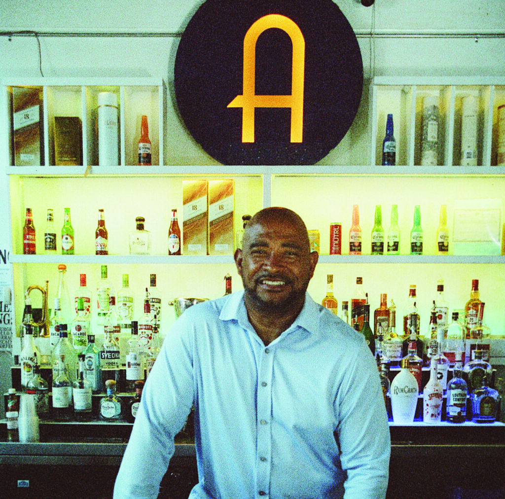 Victor Antonetti Jr. posing behind the bar counter of his event and performance space, Avalon, on State Street in Rochester, N.Y.